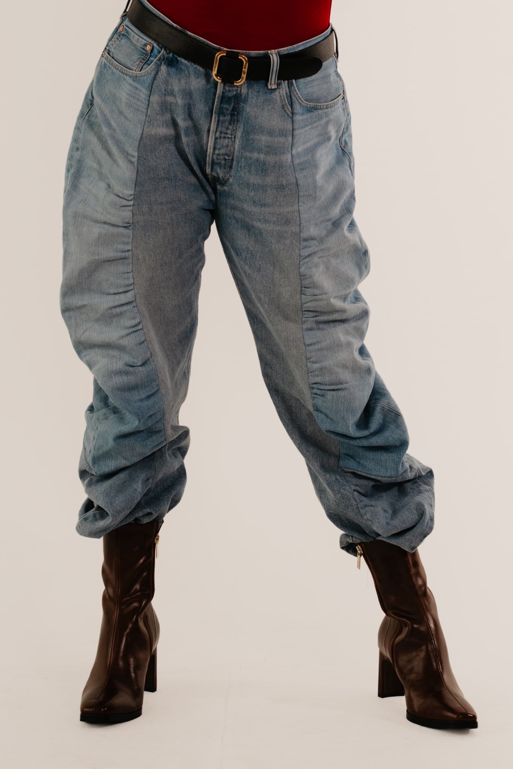 Light-wash barrel-leg jeans with a black leather belt, worn with dark brown heeled boots