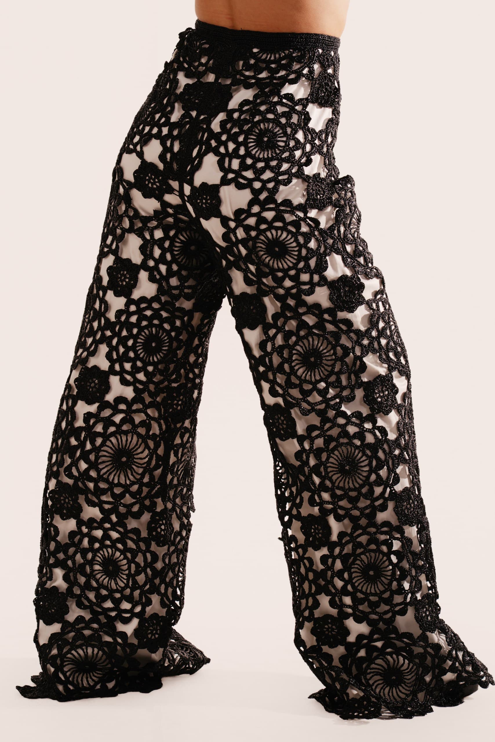 Black crochet lace wide-leg trousers worn with a black top, on a white background