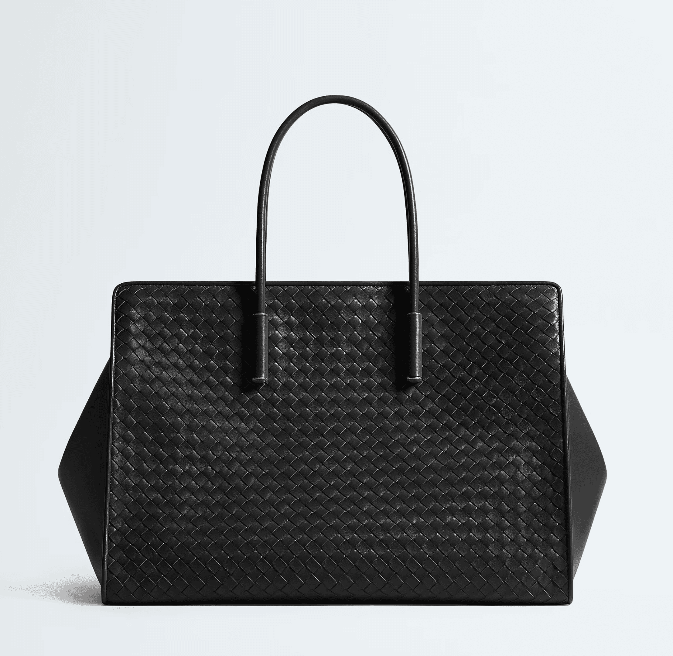 A large black woven leather tote with two top handles on a white background