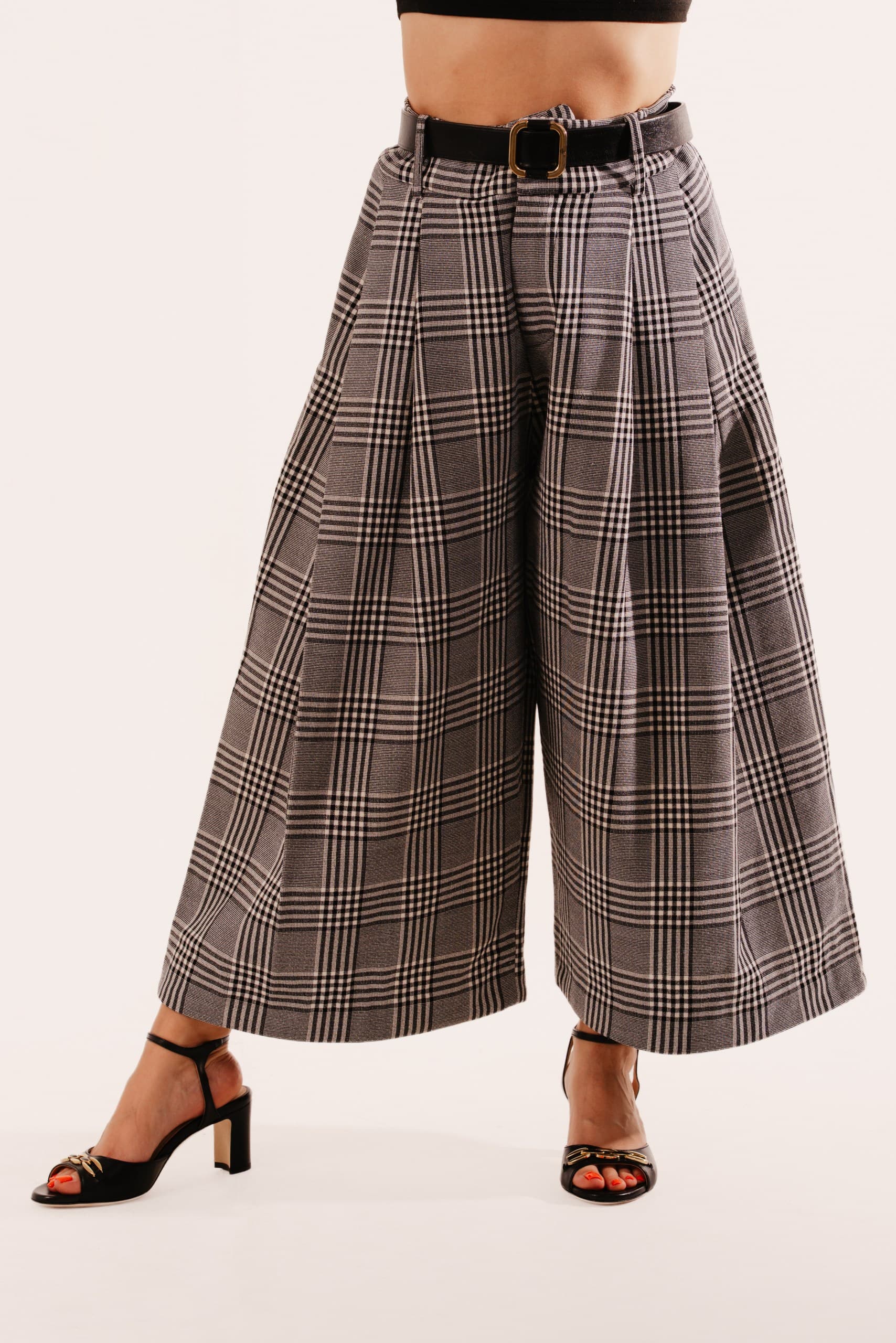 Grey and brown check wide-leg pleated trousers with a black belt, worn with black heeled sandals