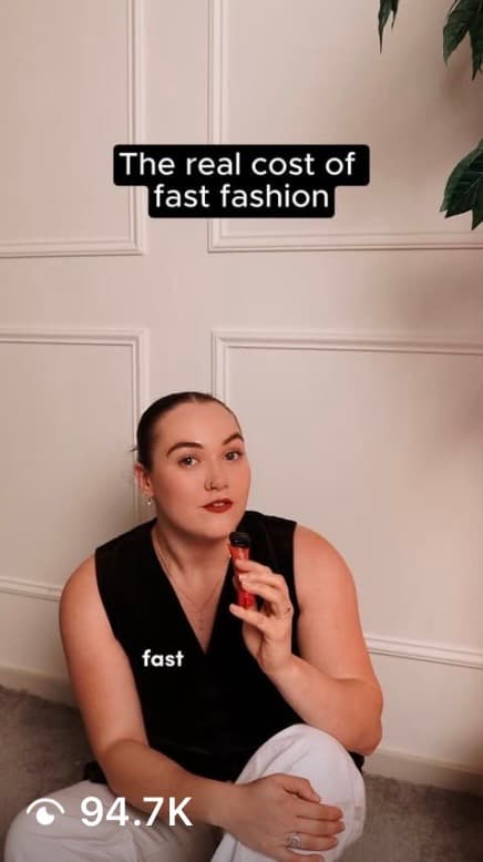 Video thumbnail: a woman in a black vest sitting against a white panelled wall holding a lipstick, captioned “The real cost of fast fashion”, 94.7K views
